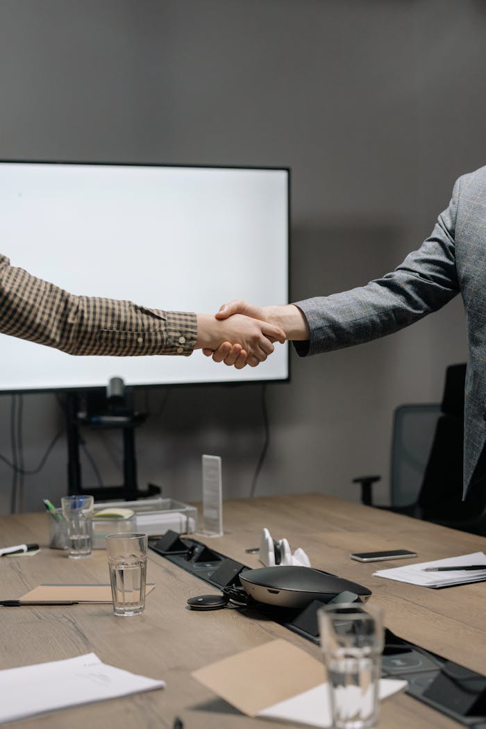 creative-02 Two business professionals shaking hands in a modern meeting room, symbolizing successful collaboration.